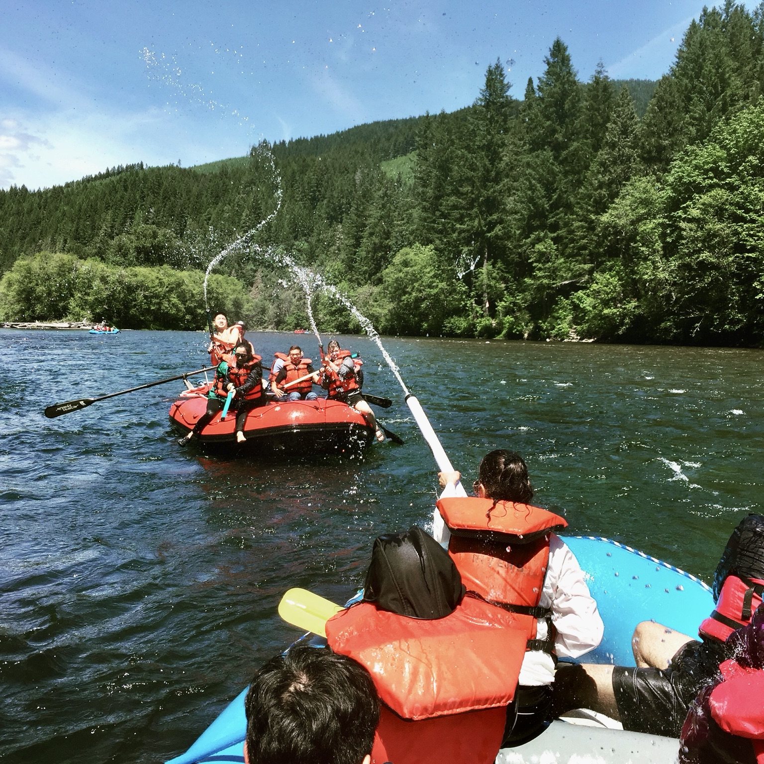 Two rafting groups enjoying a water fight on the McKenzie River